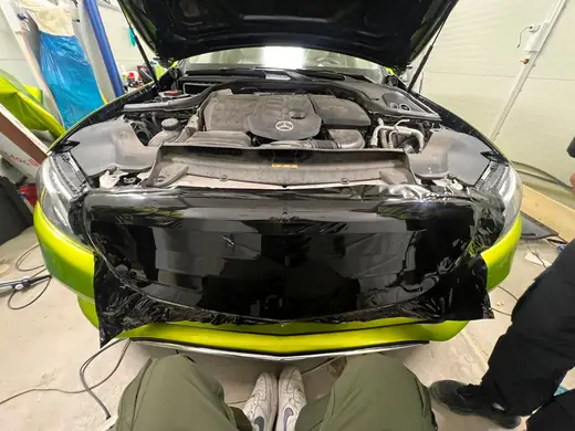 Aplikácia čiernej lesklej fólie na prednú časť Mercedesu pod kapotou