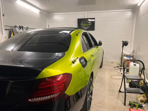 Mercedes E-Class v limetkovej fólii s čiernym kufrom — zadný trojštvrťový pohľad